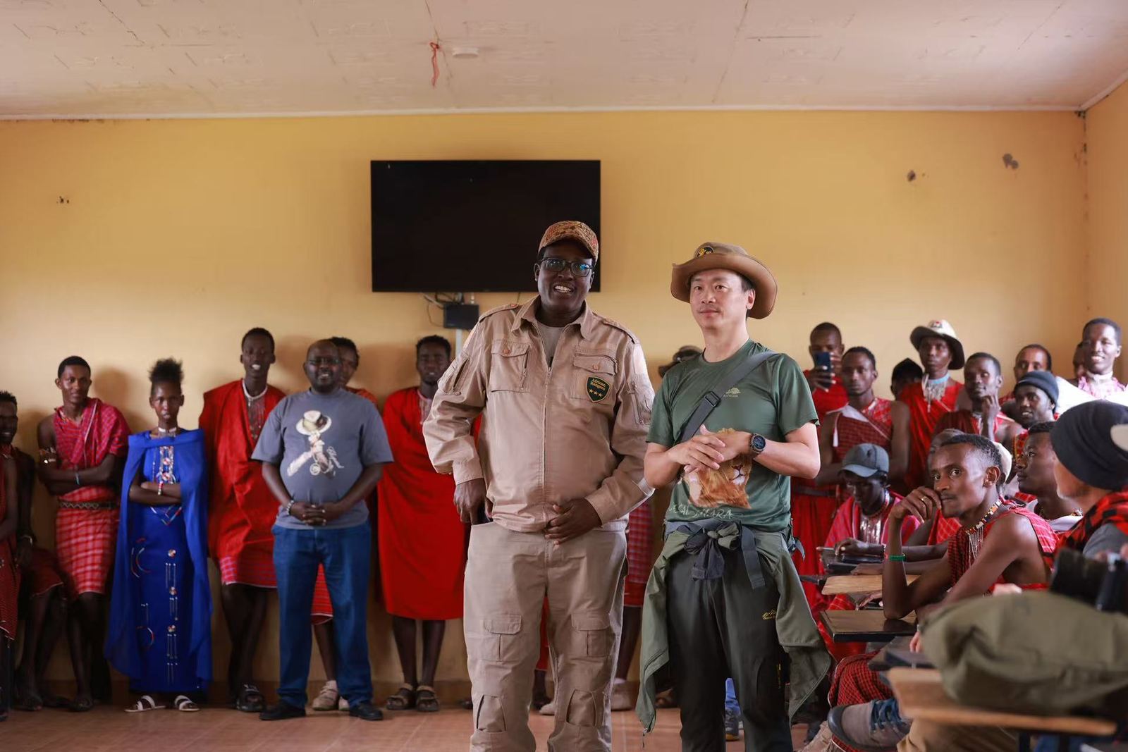 Guests and Maasai community members gathered together in a classroom